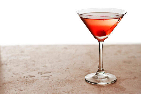closeup of a manhattan cocktail isolated on a white background garnished with a cherry
