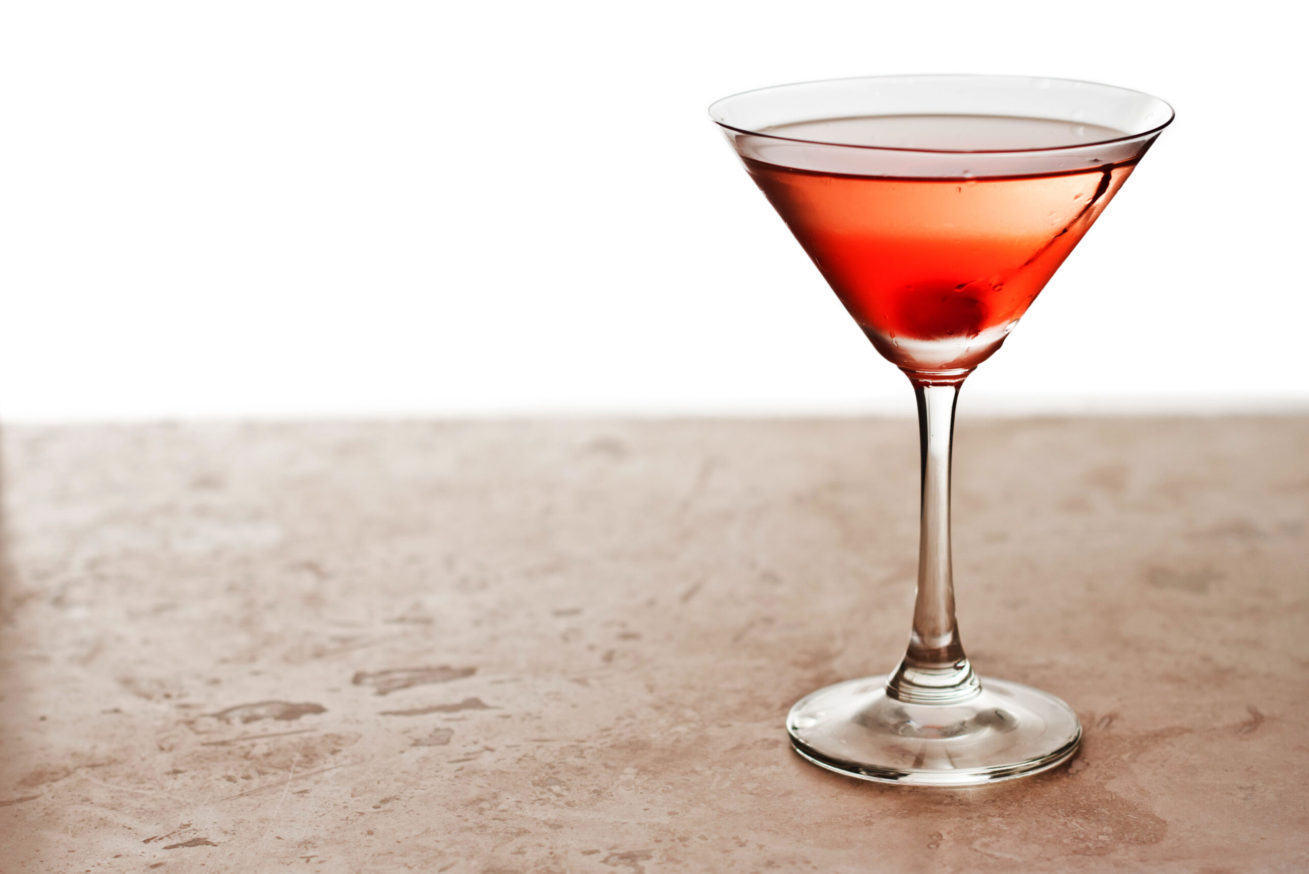 closeup of a manhattan cocktail isolated on a white background garnished with a cherry
